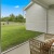 a patio with a couch and a table and a chair and a grass field