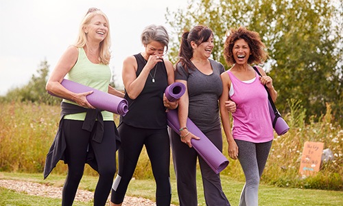 friends walking outside with yoga mats